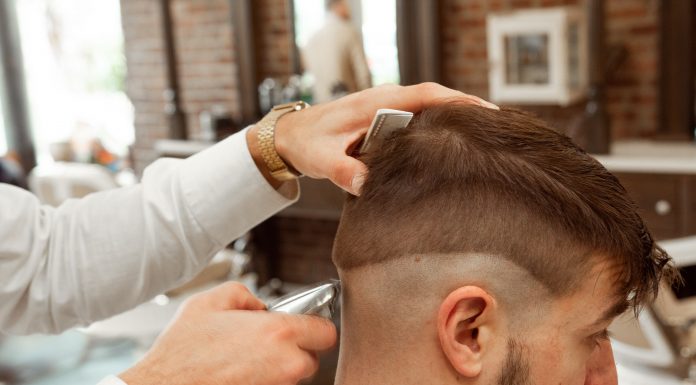 Hairstylist is cutting edgar haircut of the boy